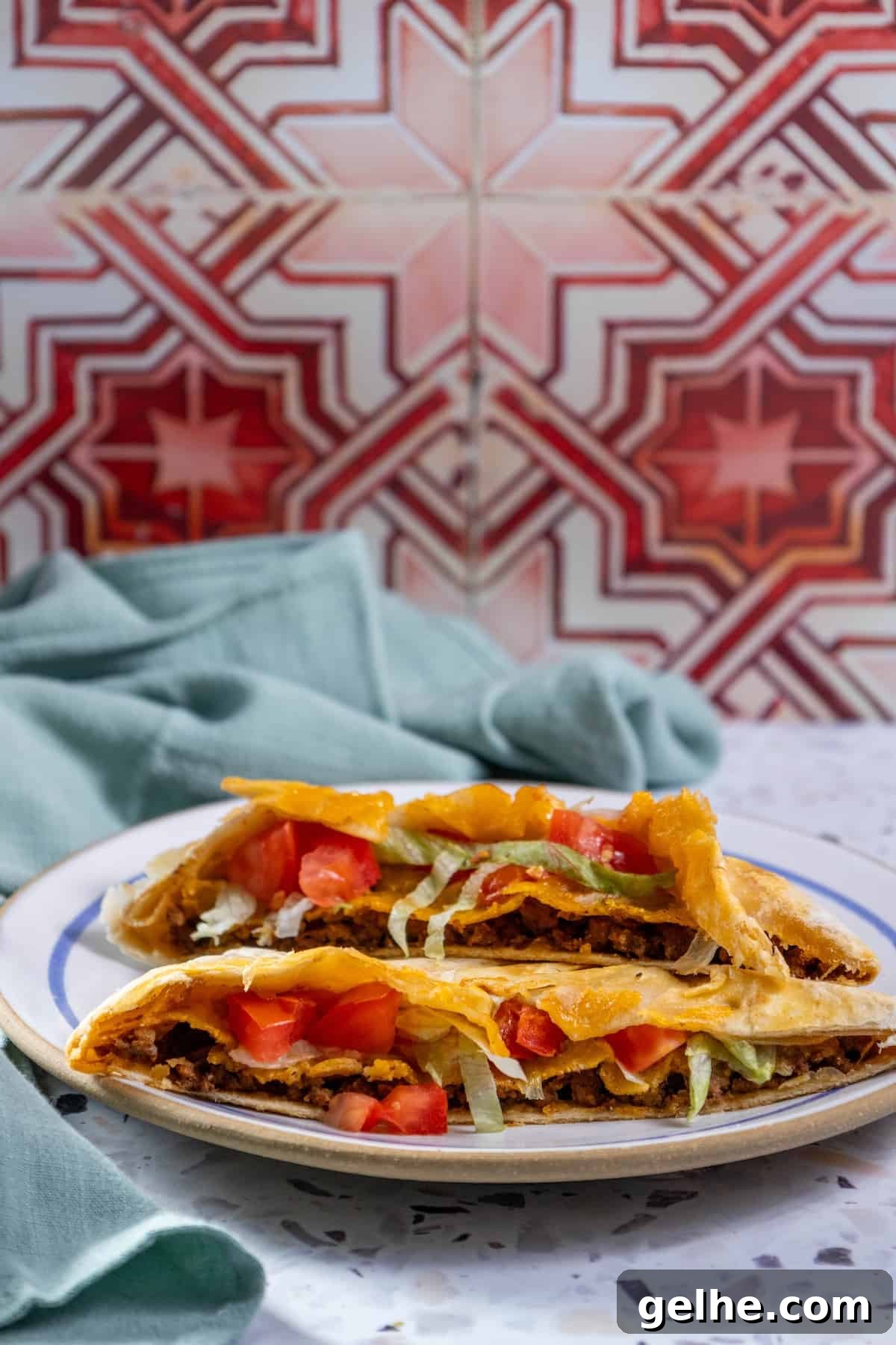 Crispy Homemade Crunchwrap Recipe: Copycat Taco Bell Wrap 4 Homemade quesadillas on a plate next to a tiled wall.