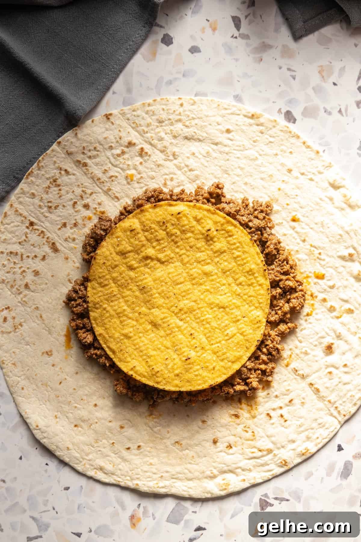 Crispy Homemade Crunchwrap Recipe: Copycat Taco Bell Wrap 6 A homemade crunchwrap with a yellow filling, sitting on a table.