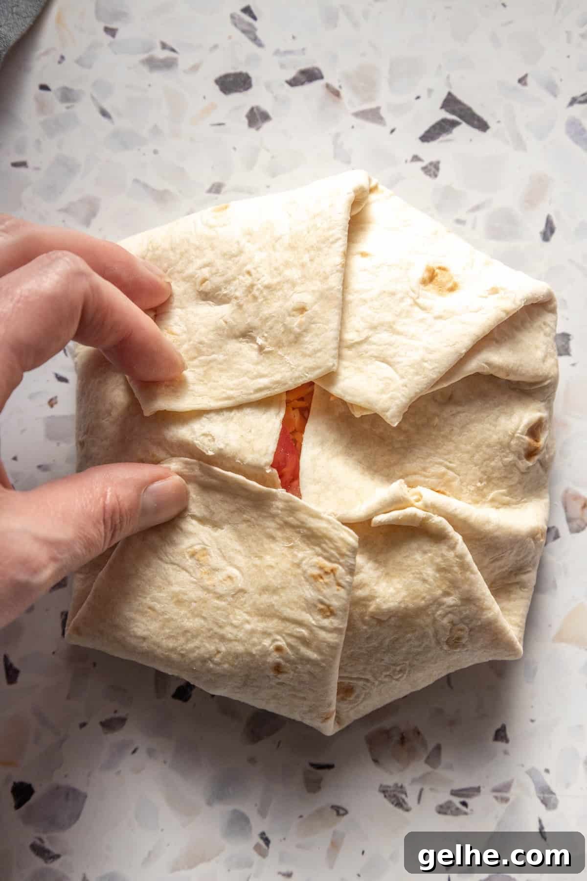 Crispy Homemade Crunchwrap Recipe: Copycat Taco Bell Wrap 10 A person holding a homemade crunchwrap on a table.