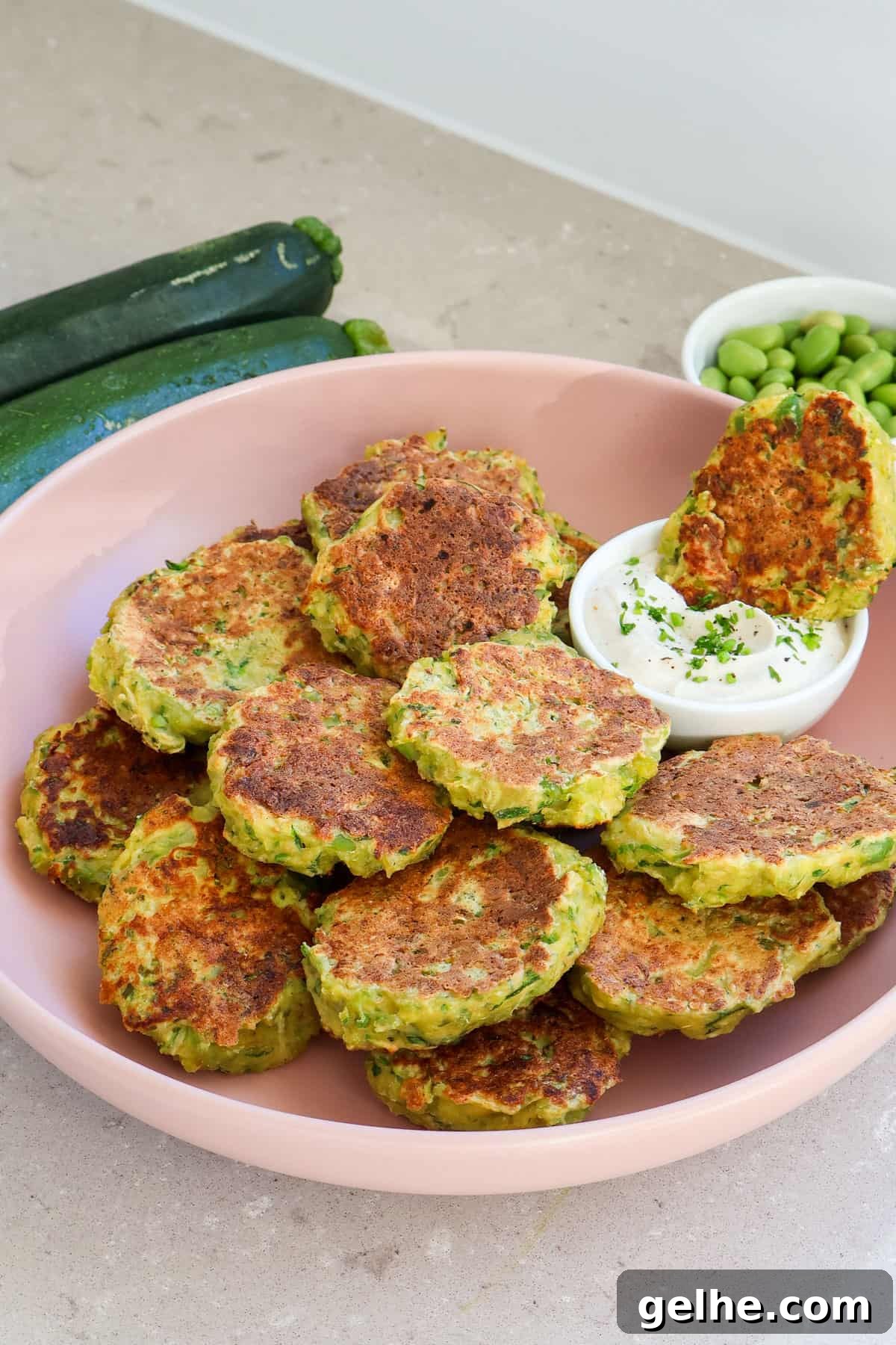 Side shot of edamame fritters dipped in yoghurt sauce.