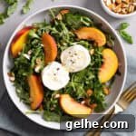 Close up of a serving of arugula burrata salad with peaches and almonds.