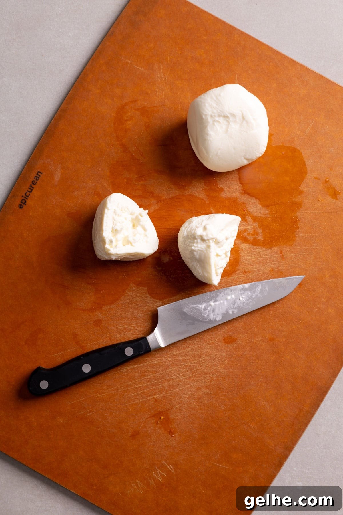Burrata cheese getting sliced on a cutting board.