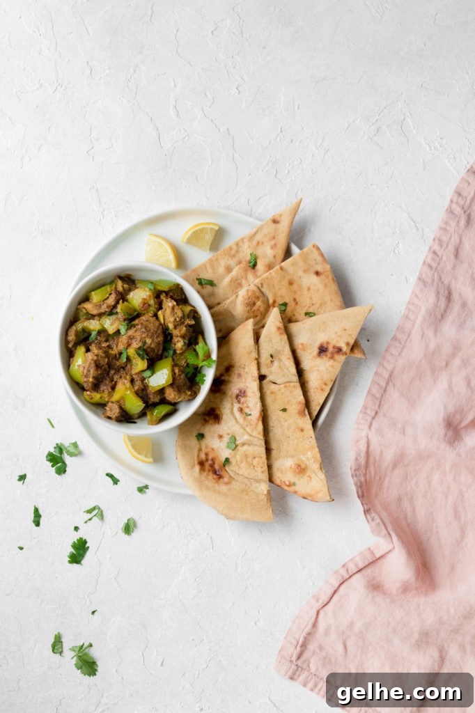 Instant Pot Goat Curry with Bell Peppers 2 Bowl of Instant Pot Goat and Bell Pepper Curry garnished with cilantro on top of a white plate with naan and lemon wedges.