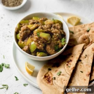 Instant Pot Goat Curry with Bell Peppers 4 Bowl of Instant Pot Goat and Bell Pepper Curry garnished with cilantro on top of a white plate with naan and lemon wedges.