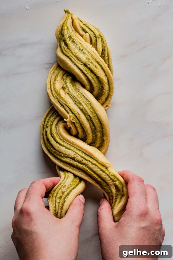 Hands wrap the dough around each other.