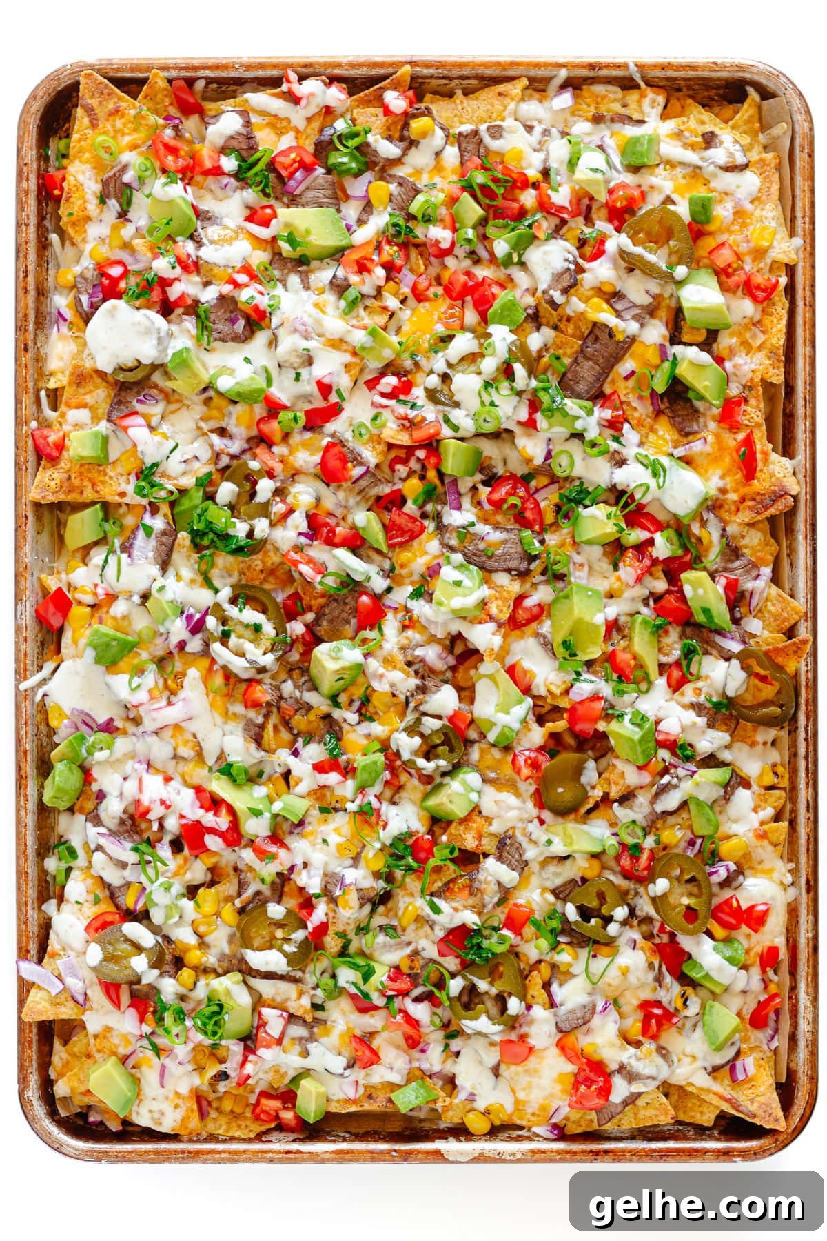Loaded Steak Nachos Recipe with Melted Cheese 7 Steak nachos on a sheet pan.