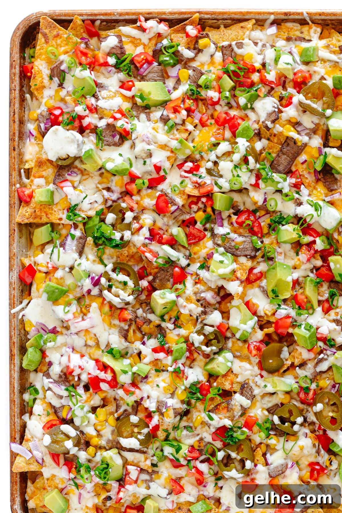 Loaded Steak Nachos Recipe with Melted Cheese 9 Closeup of leftover steak nachos on a sheet pan.
