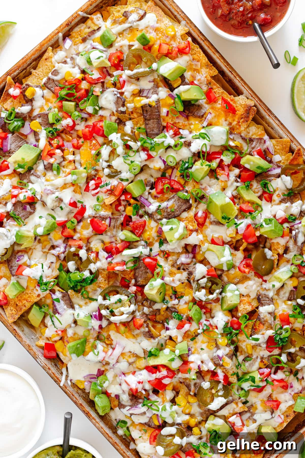 Loaded Steak Nachos Recipe with Melted Cheese 10 Leftover steak nachos on a sheet pan.