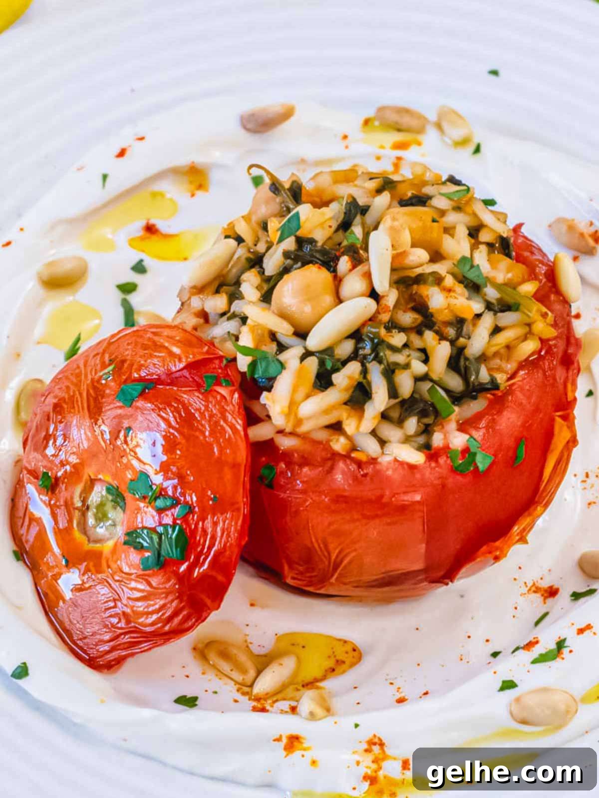 Oven-Baked Stuffed Tomatoes with Herb Breadcrumbs 3 Super close-up of a stuffed tomato served on a bed of Greek yogurt, with the top off to reveal a filling of rice, chickpeas, and herbs.