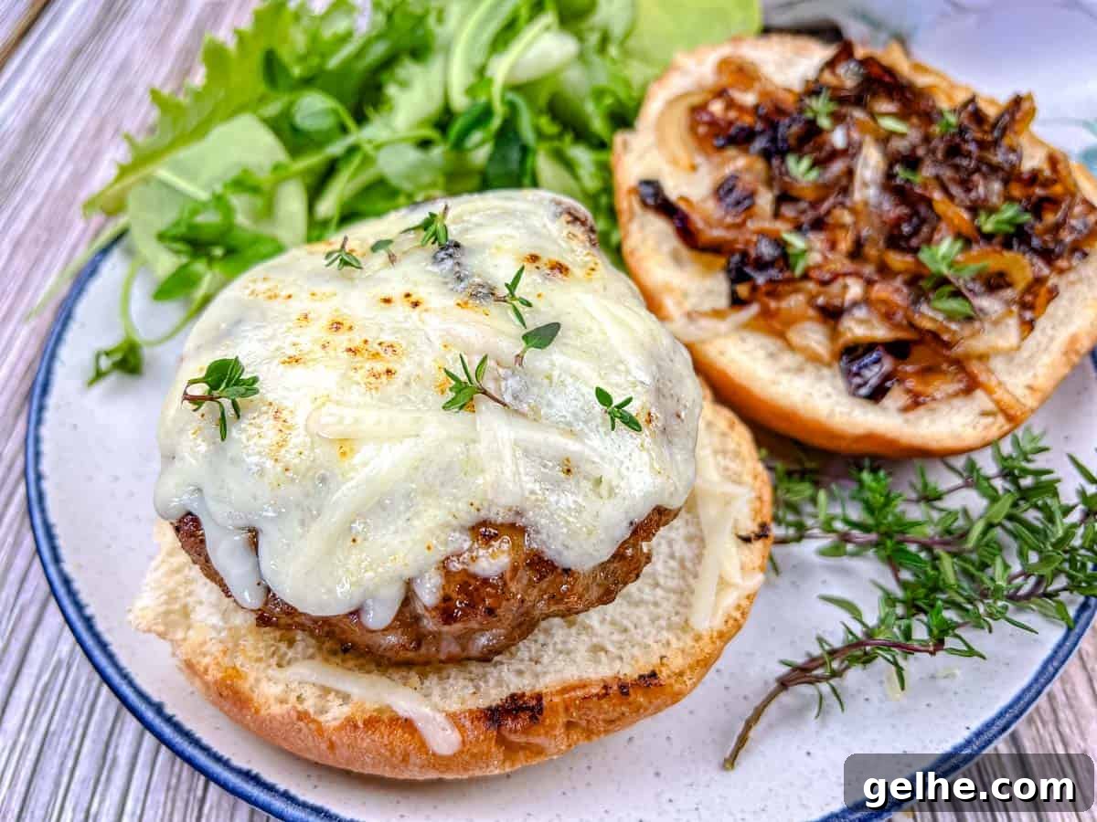 Close-up shot of Grilled French Onion Pork Burgers on a Ninja Woodfire Outdoor Grill topped with cheesy onion on a plate.