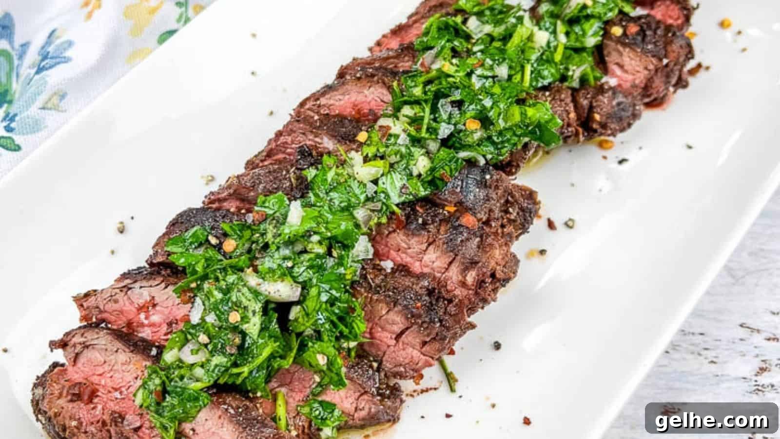 A plate of sliced Grilled Hanger Steaks with Chimichurri, served on a white rectangular dish.