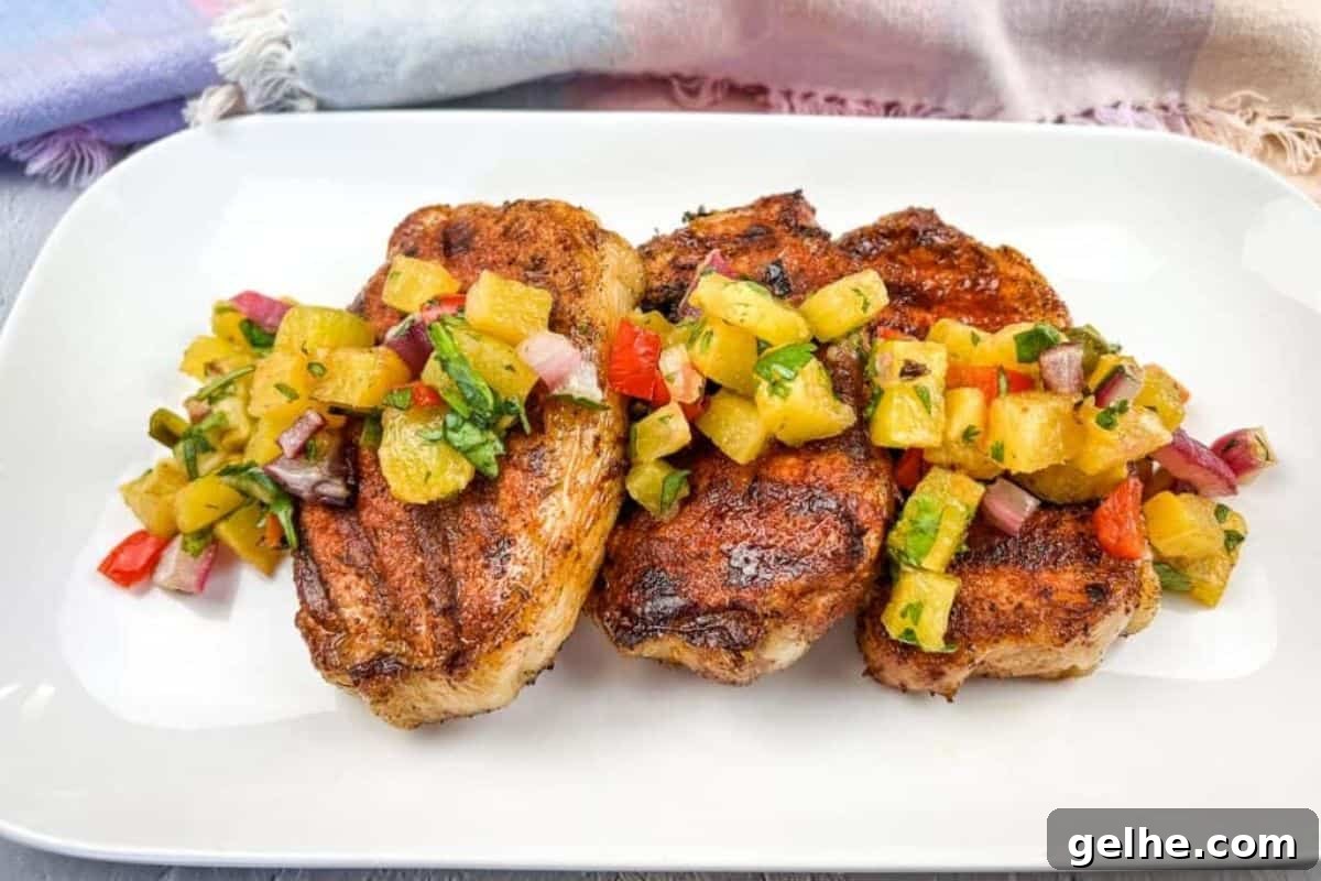 Grilled pork chops with pineapple salsa on a white plate.