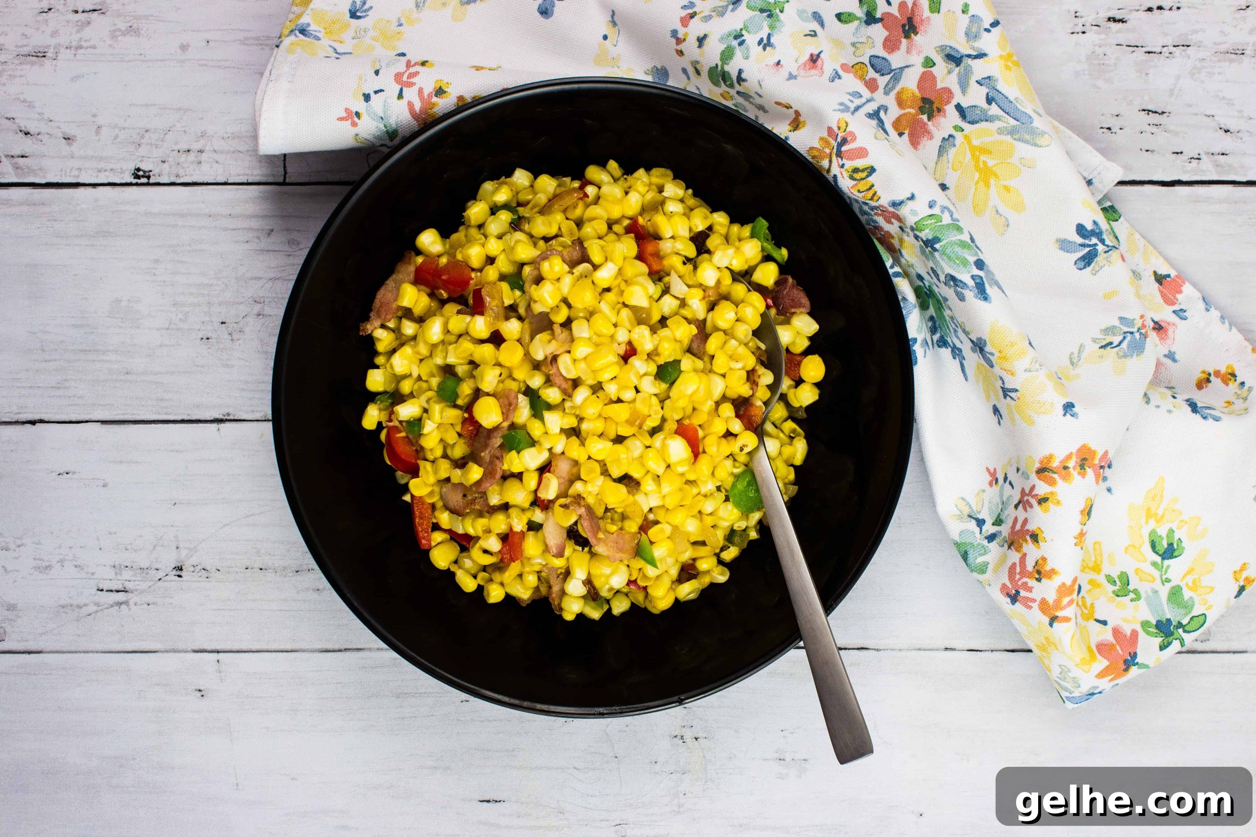 Texas Corn Succotash in a black bowl with spoon.
